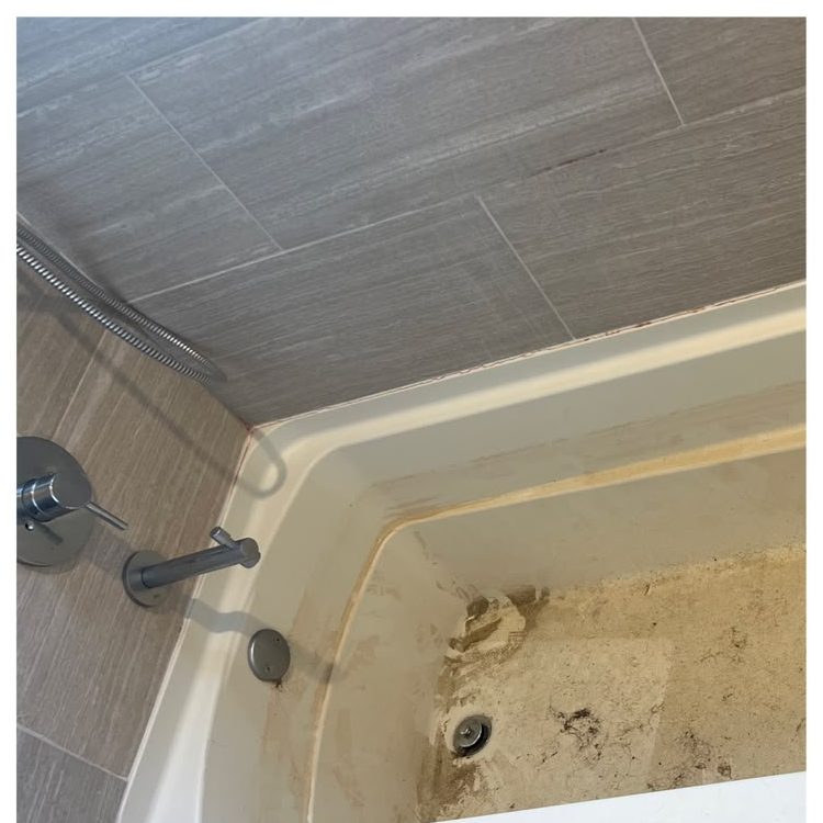 The same bathtub before cleaning, covered in construction dust